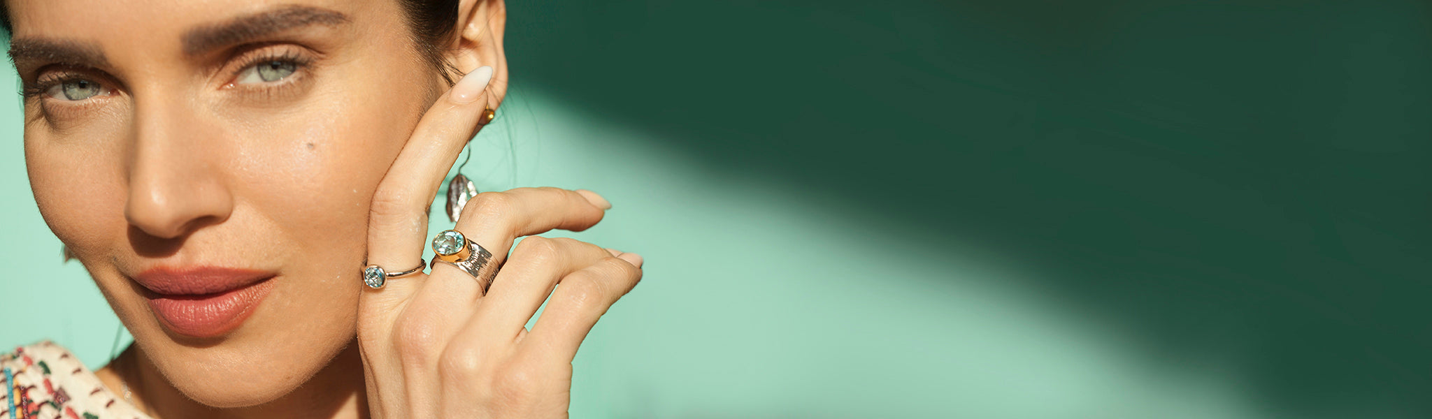 Model showcasing stunning handcrafted silver and gold rings with vibrant blue topaz gemstones, part of Christin Ranger's ring collection.