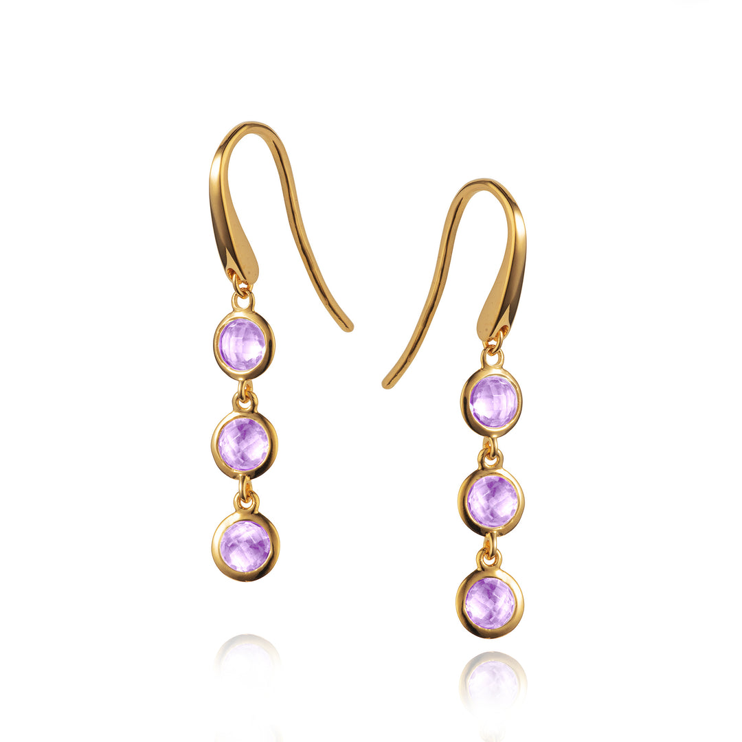Gold earrings with purple gemstones on a white background