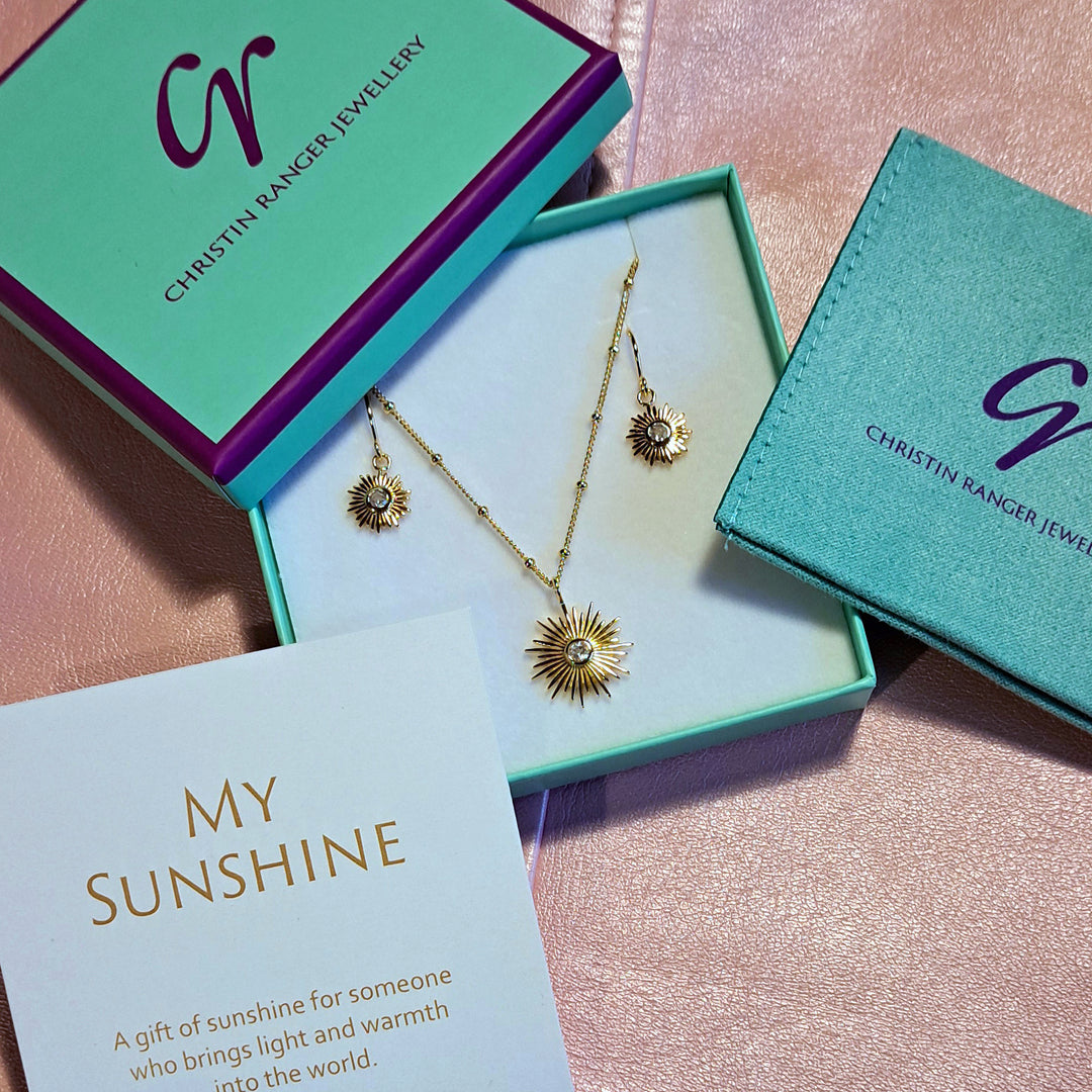 Packaging for the gold "sunshine" necklace and earring set with white topaz including gift card 