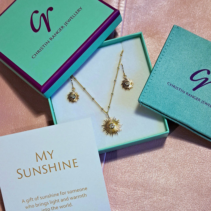 Packaging for the gold "sunshine" necklace and earring set with white topaz including gift card 