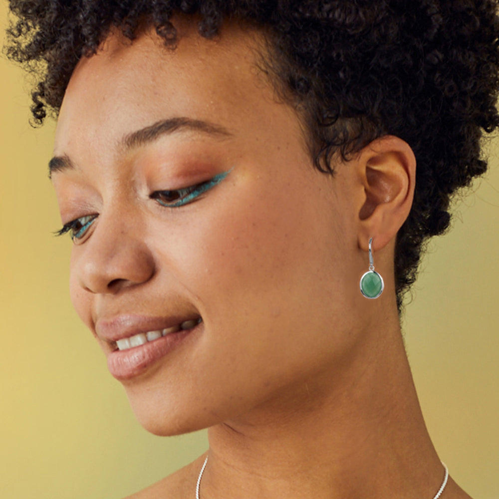 Close-up of a woman wearing silver green aventurine earrings with a yellow background
