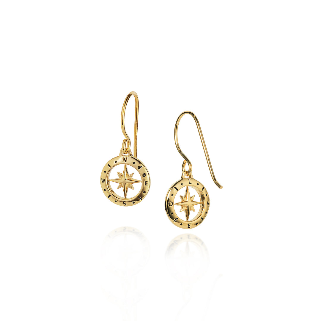 Gold compass earrings on a white background