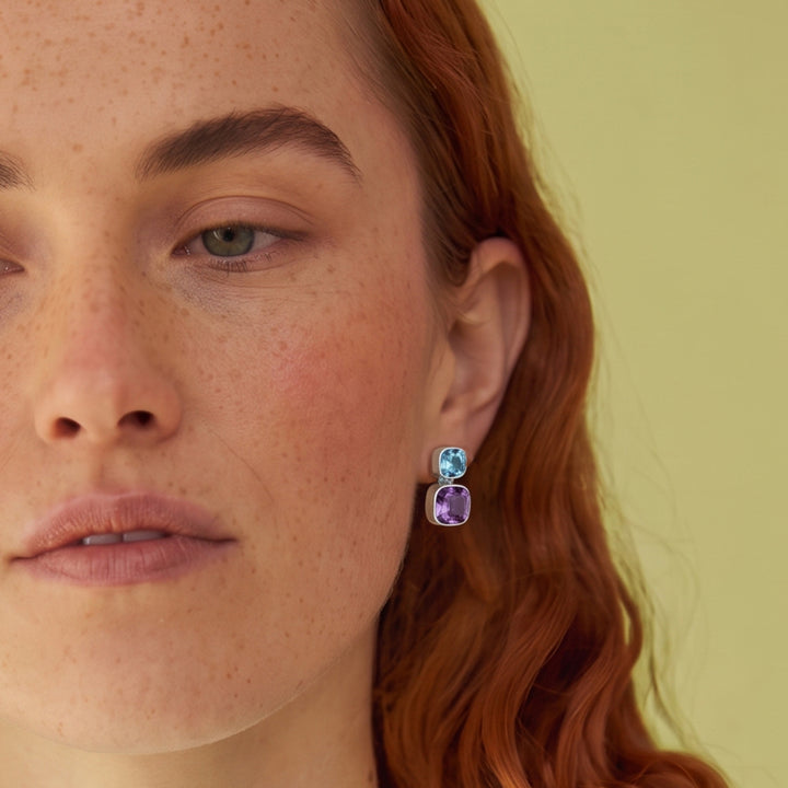 Close-up of woman wearing Amethyst and blue topaz stud earrings in sterling silver