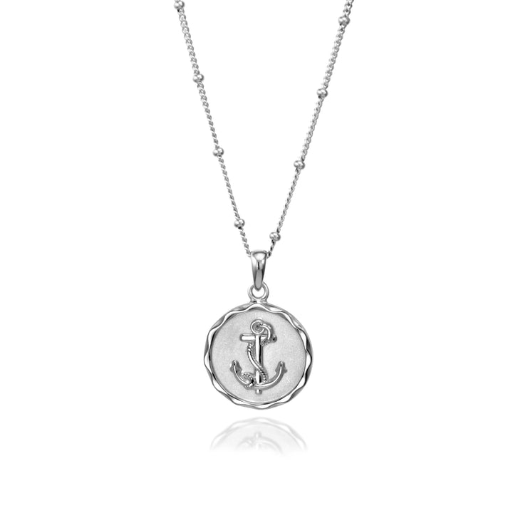 Silver anchor necklace on a beaded chain against  white background