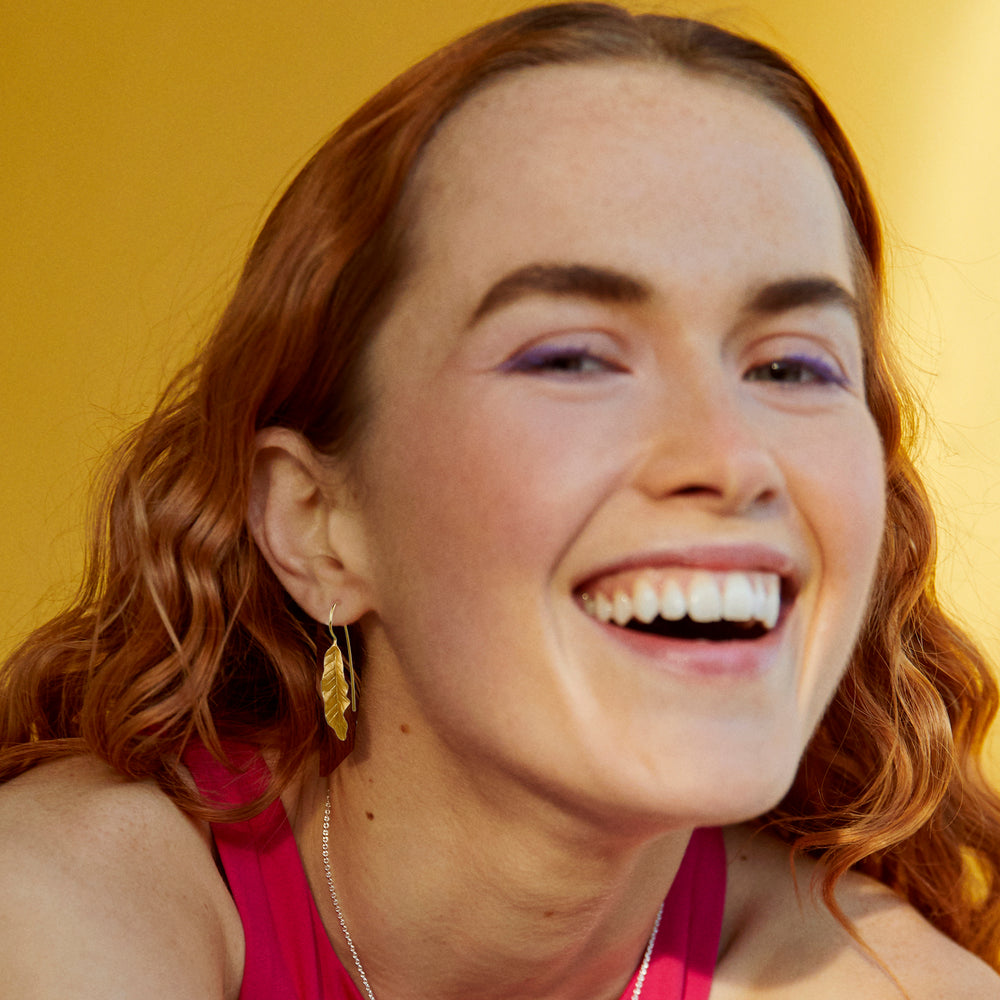 Woman with red hair wearing gold leaf earrings