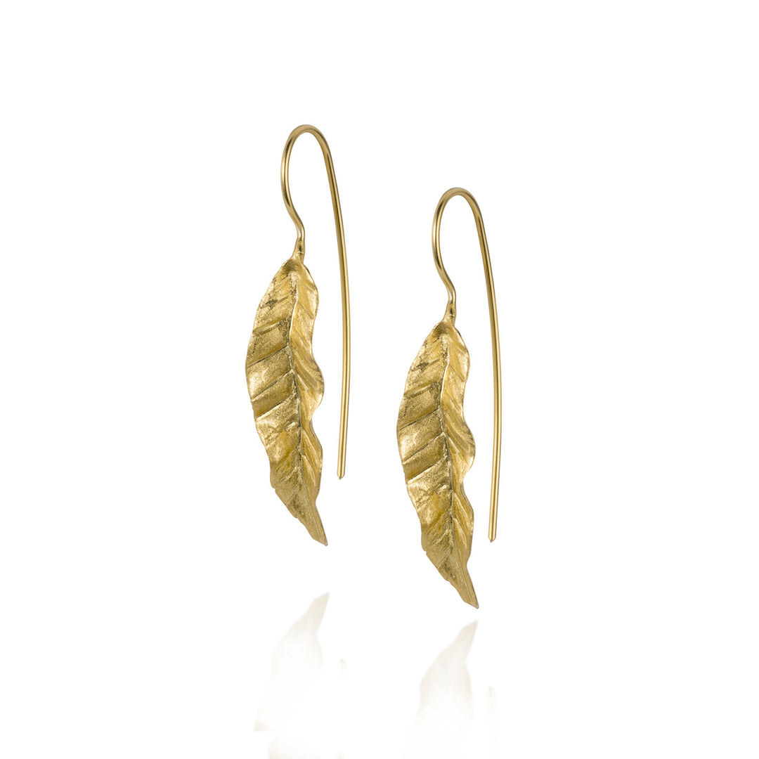 Gold leaf-shaped earrings on a white background