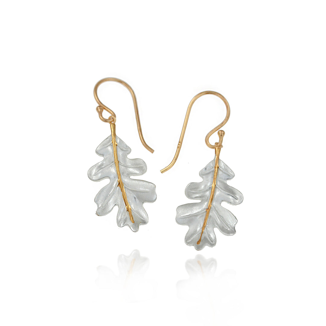 Pair of oak leaf-shaped earrings with gold accents on a white background