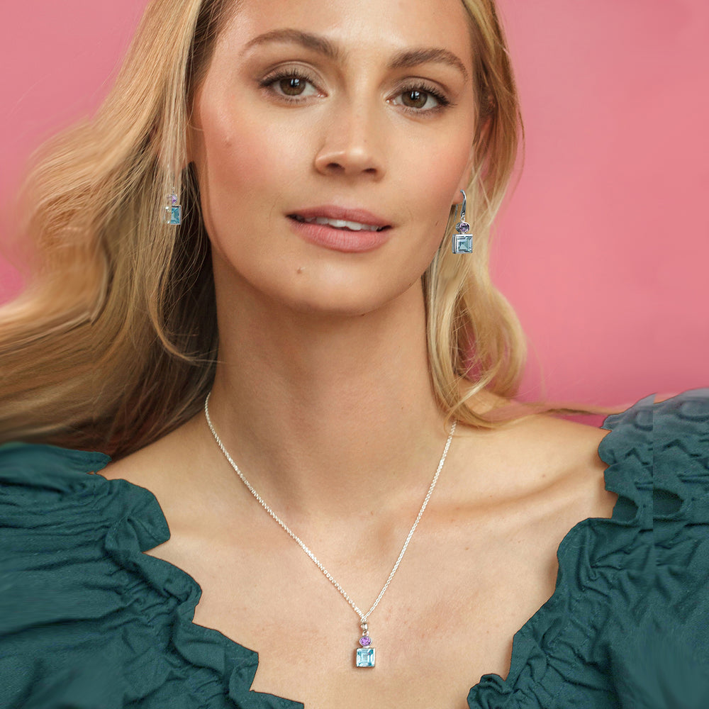 Woman wearing blue topaz & amethyst drop earring and necklace set in sterling silver