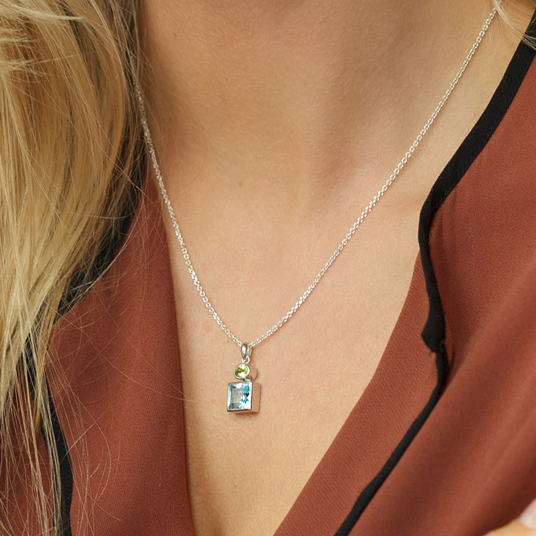 Close-up of woman wearing a square peridot and oval peridot pendant necklace in sterling silver