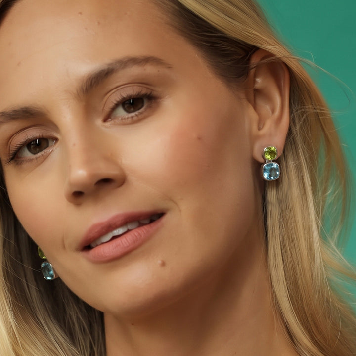 Woman wearing blue topaz and peridot stud earrings in sterling silver