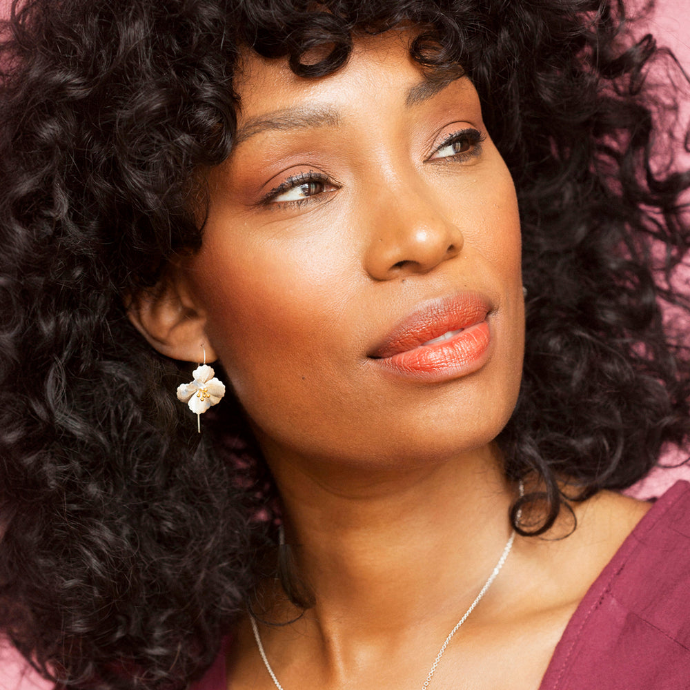 Close-up of  a woman wearing silver and gold flower earrings 