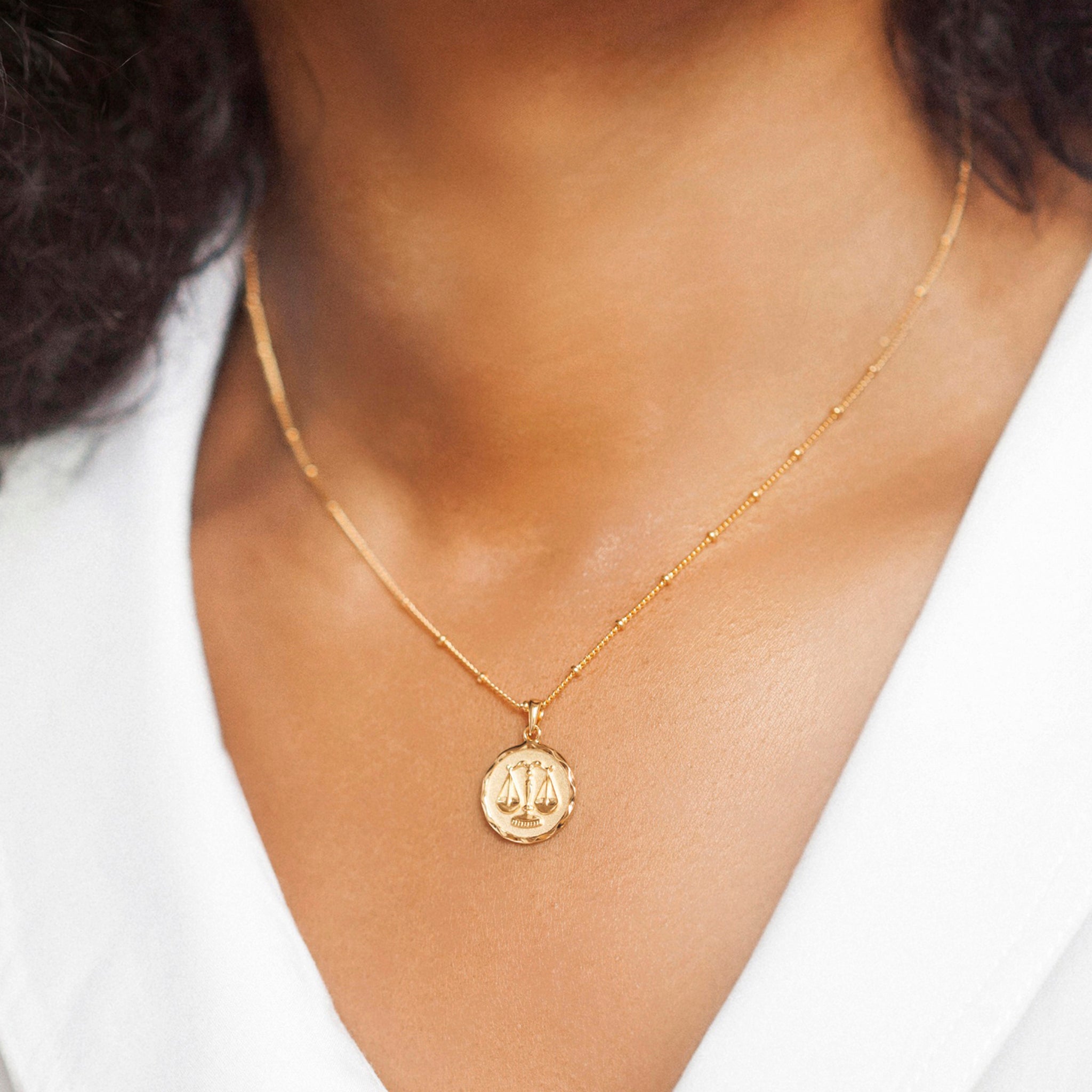 Close-up of a woman wearing a christin ranger gold vermeil star sign necklace pendant