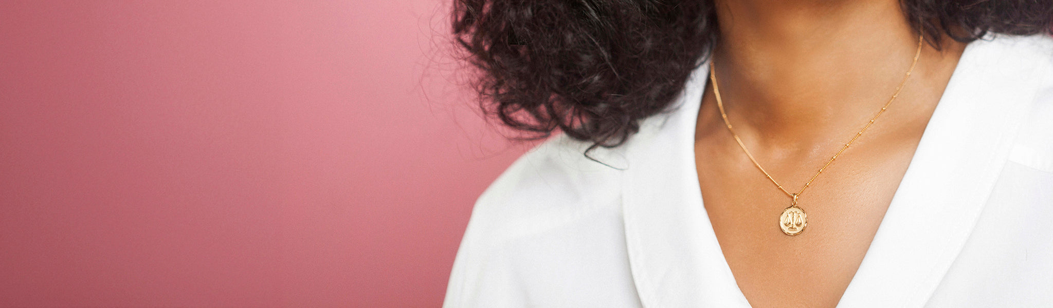 Close-up of a woman wearing a gold vermeil zodiac star sign pendant