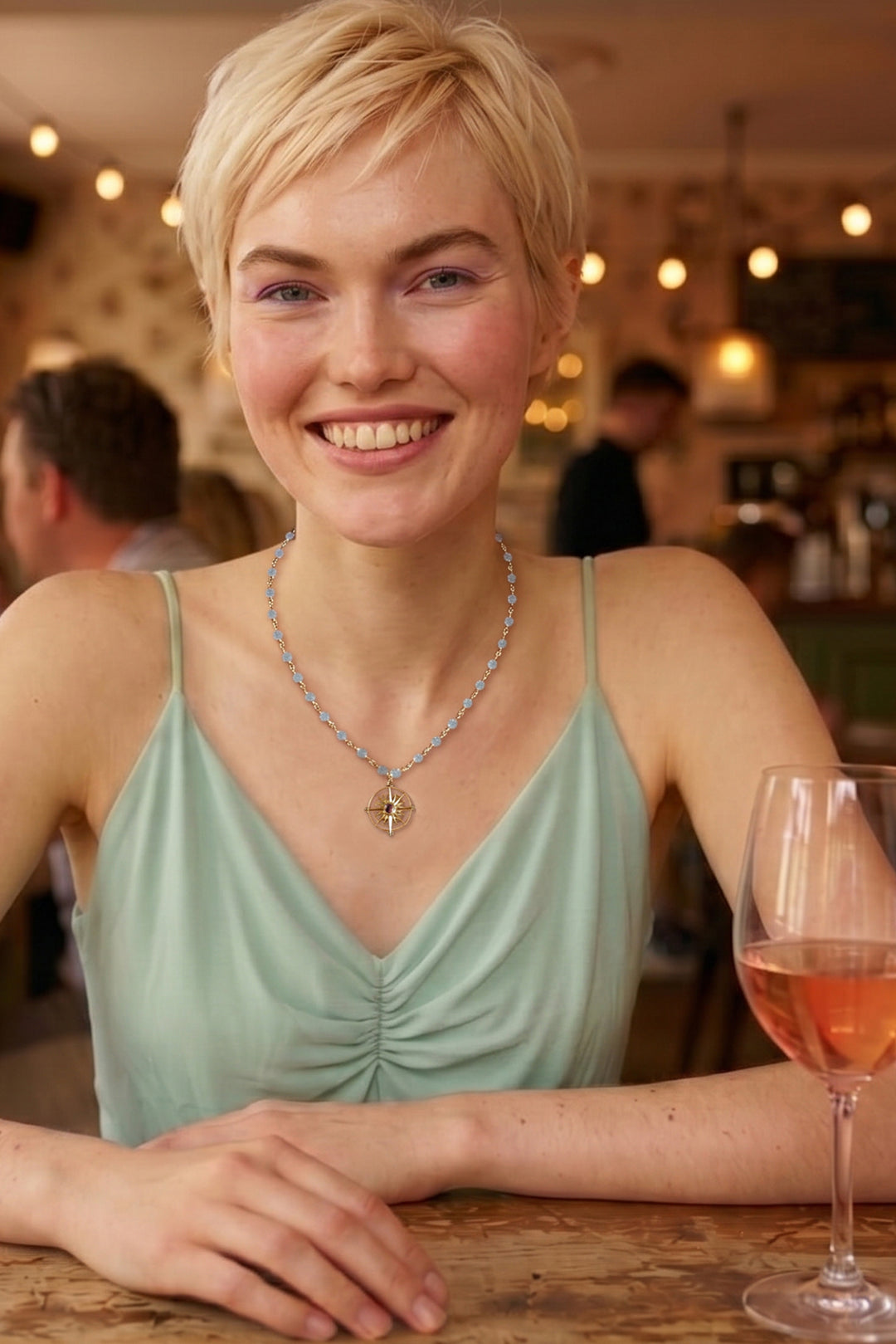 Smiling woman wearing a Christin Ranger necklace in gold and natural gemstones.