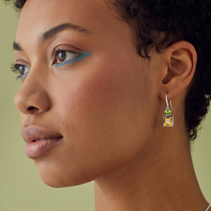 Close-up of woman wearing square citrine and oval peridot drop earrings set in sterling silver