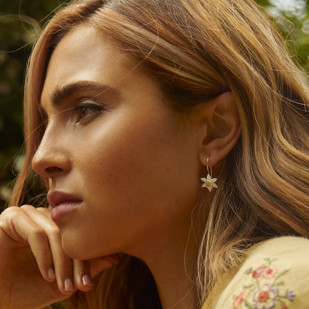 Close-up of a woman with daffodil drop earrings outdoors