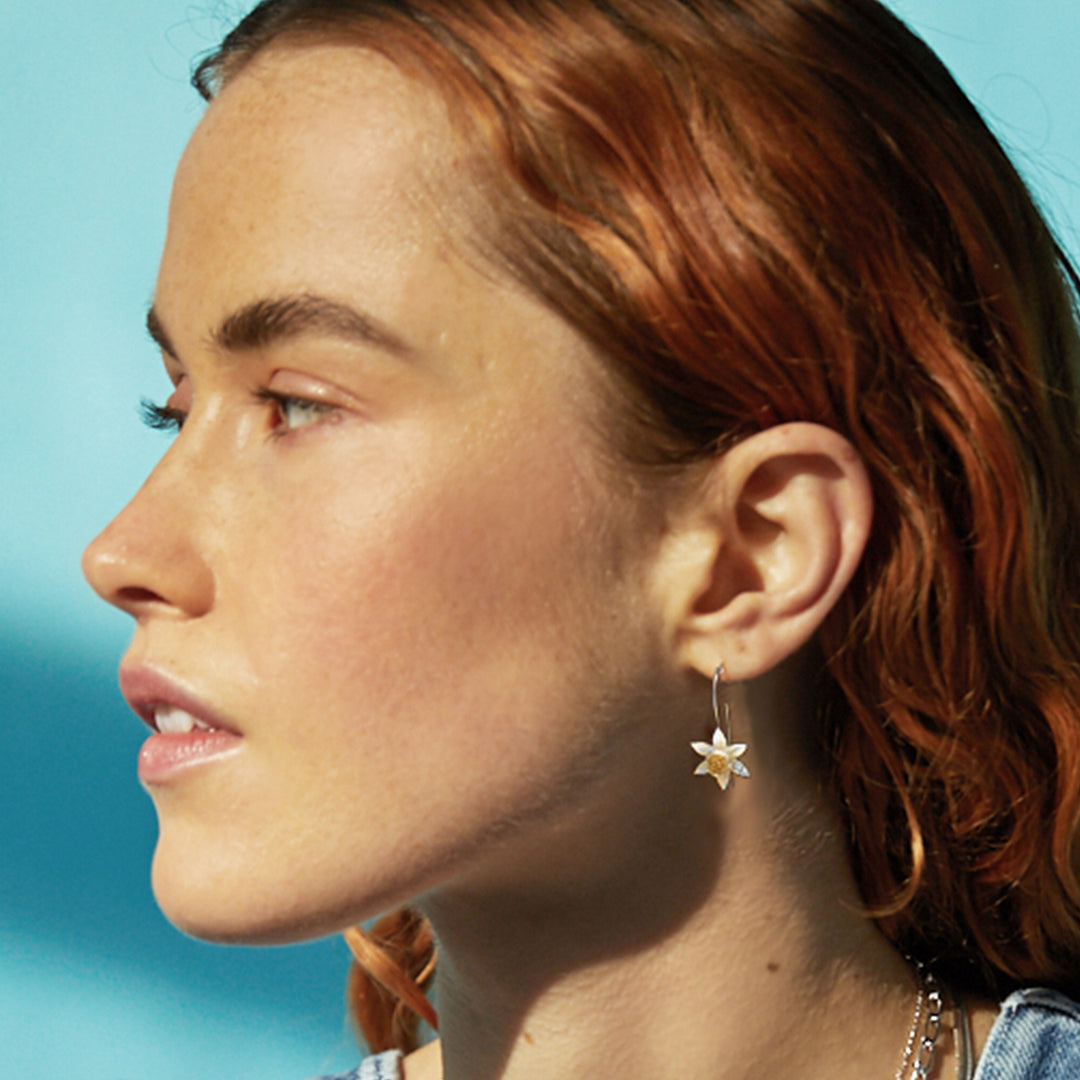 Model wearing sterling silver daffodil flower drop earrings with gold centres