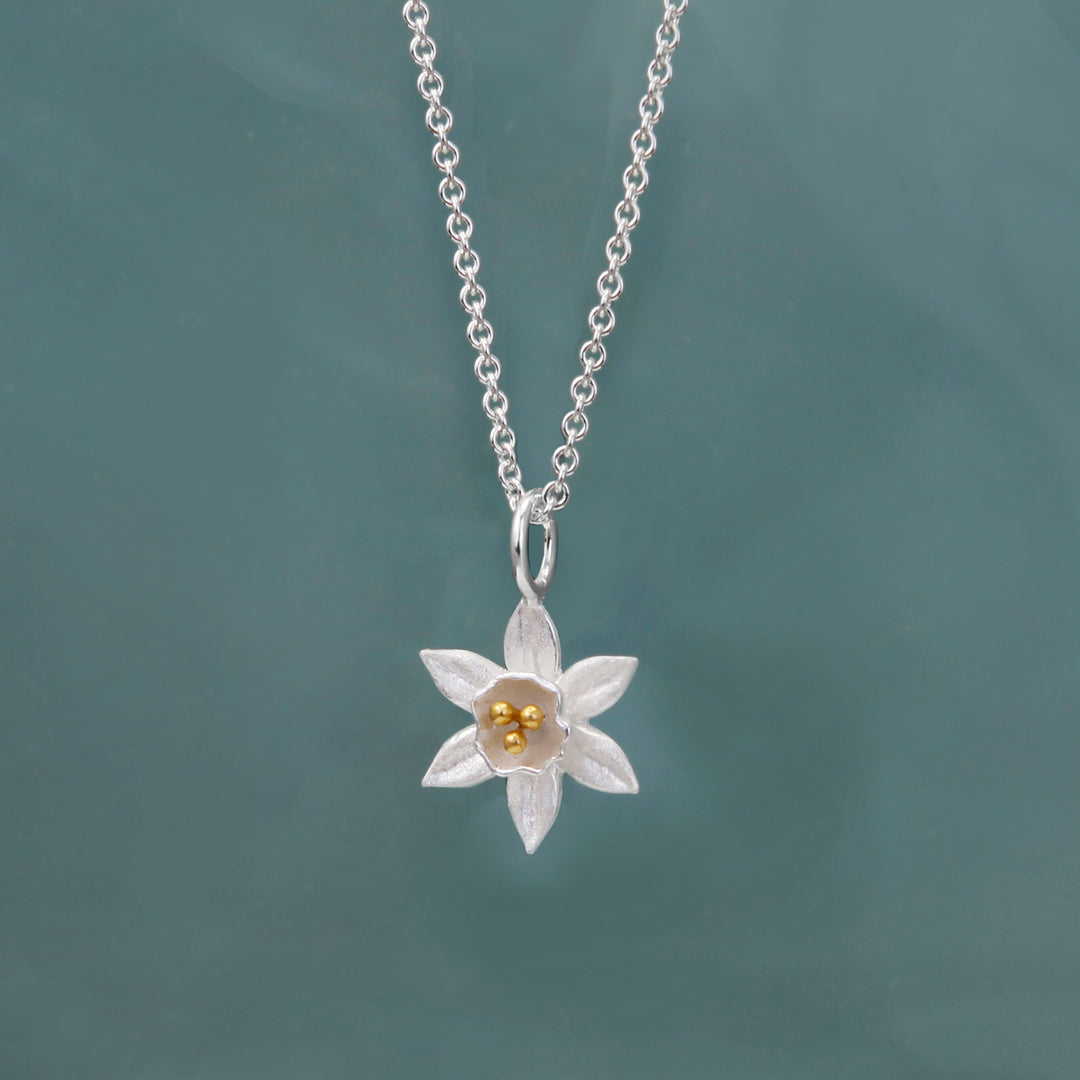 Silver daffodil necklace with gold details on a green background