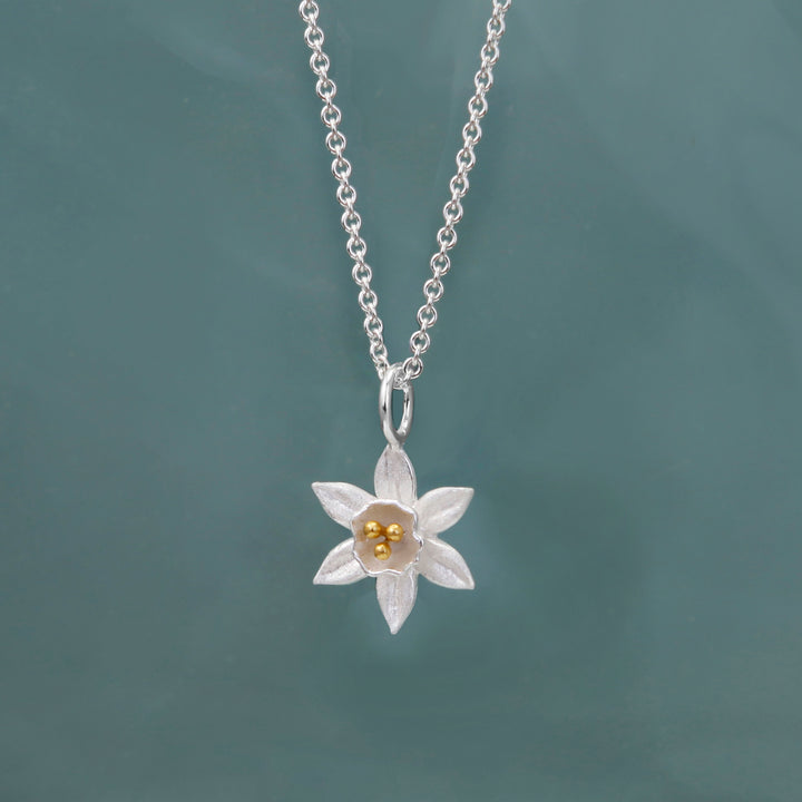 Silver daffodil necklace with gold details on a green background