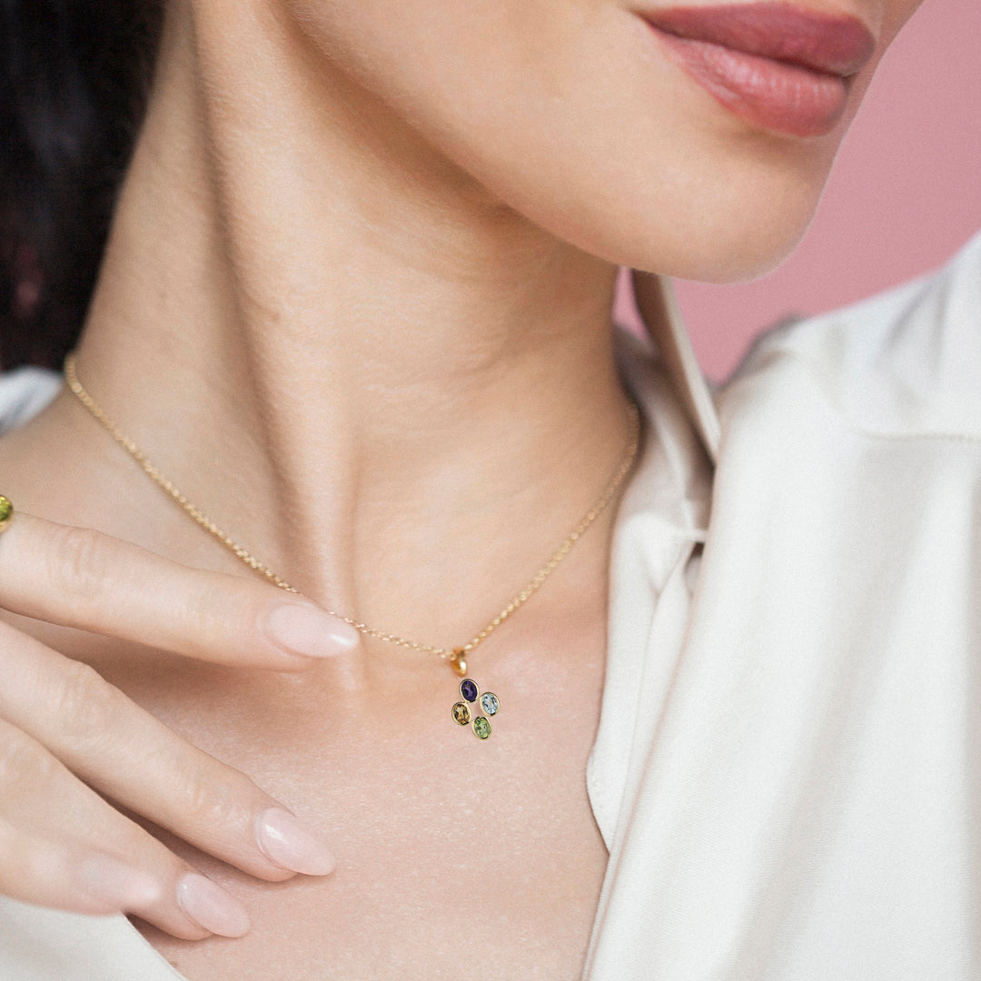 Close-up of a person wearing a delicate gold necklace with colorful gemstone cabachons