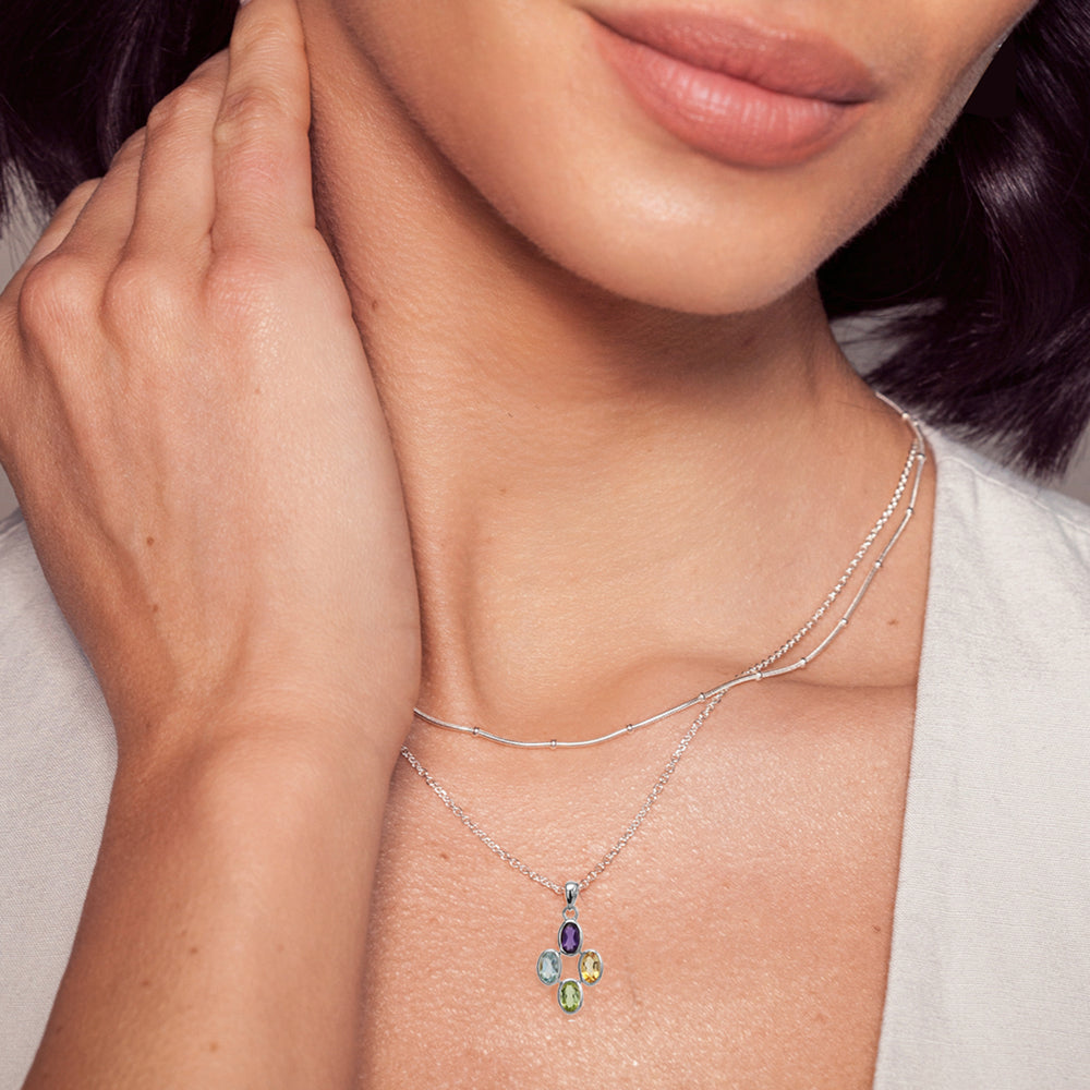 Close-up of model wearing a multi-stone silver pendant and chain