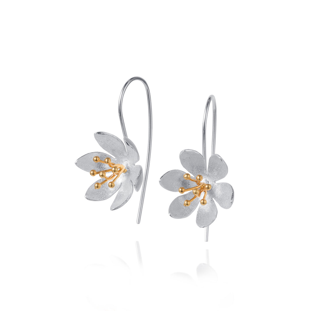 Flower-shaped silver earrings with gold centers on a white background
