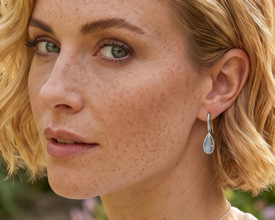 Side view of woman wearing blue topaz pear cut earrings in sterling silver