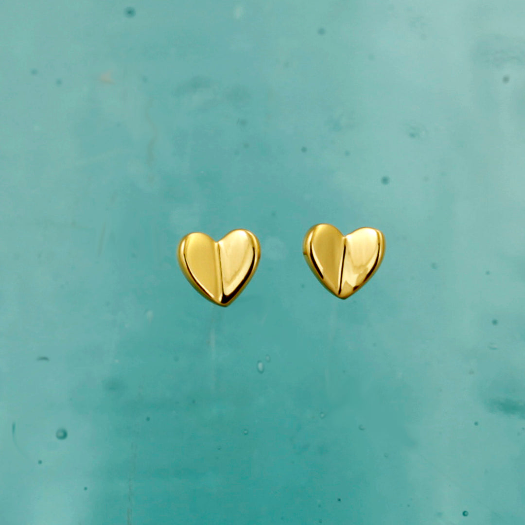 Gold heart-shaped earrings on a light blue background