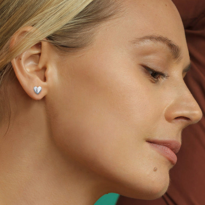 Close-up of a woman wearing a heart-shaped silver stud earring.