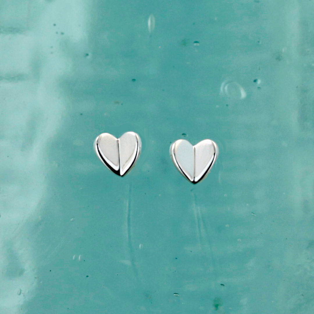 Heart-shaped silver earrings on a textured light blue background