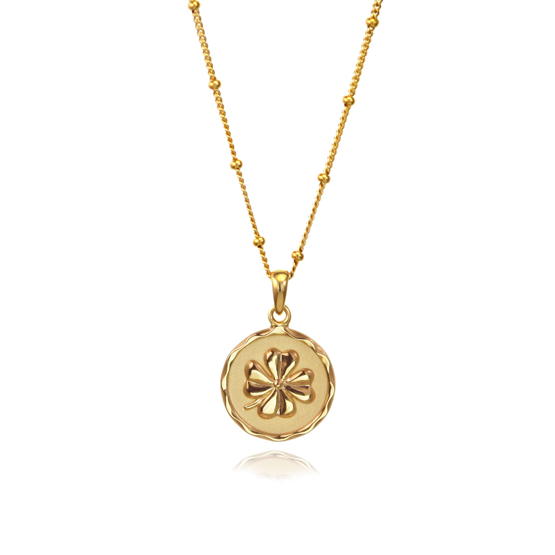 Gold four-leaf clover lucky charm pendant  with a beaded chain on a white background