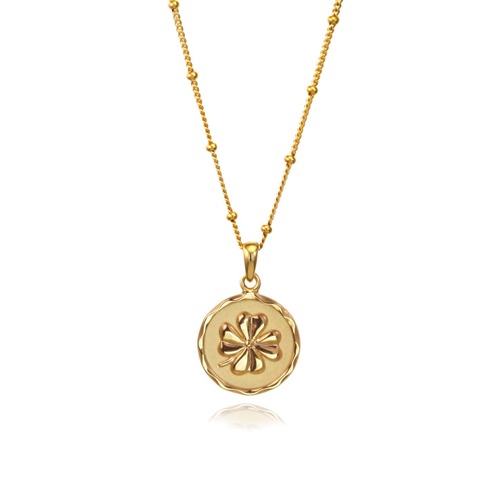 Gold four-leaf clover lucky charm pendant  with a beaded chain on a white background