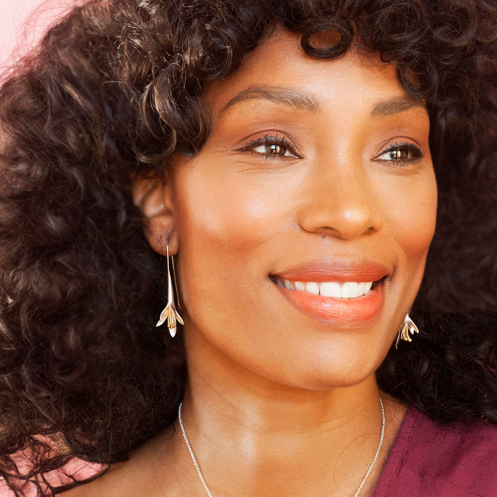 Woman wearing silver and gold flower earrings and smiling