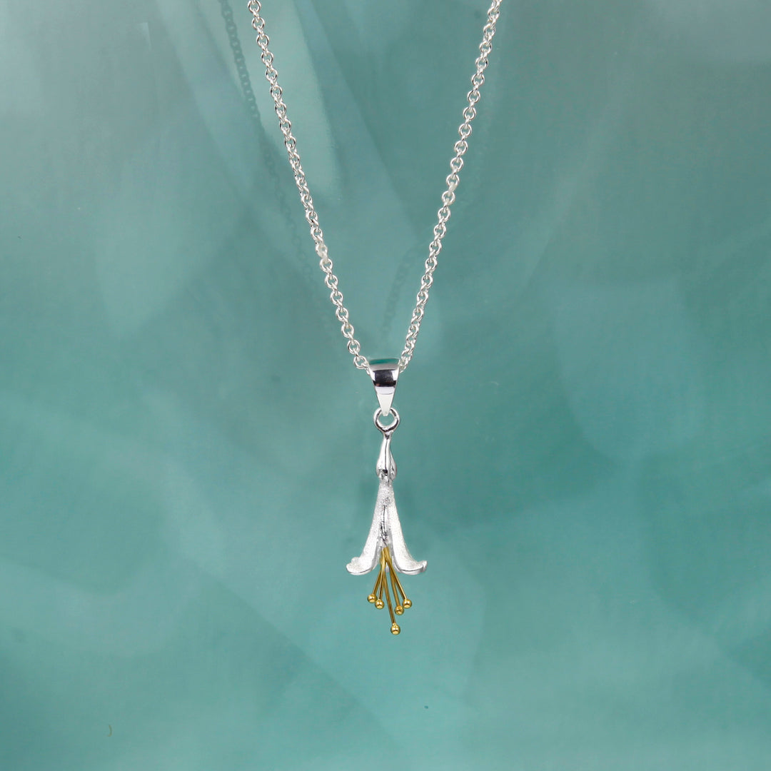 Silver necklace with a fuchsia floral pendant on a light green background