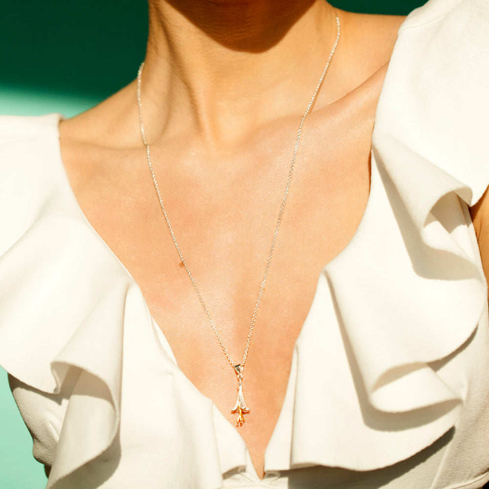 Close up of model wearing silver fuchsia necklace with a white dress