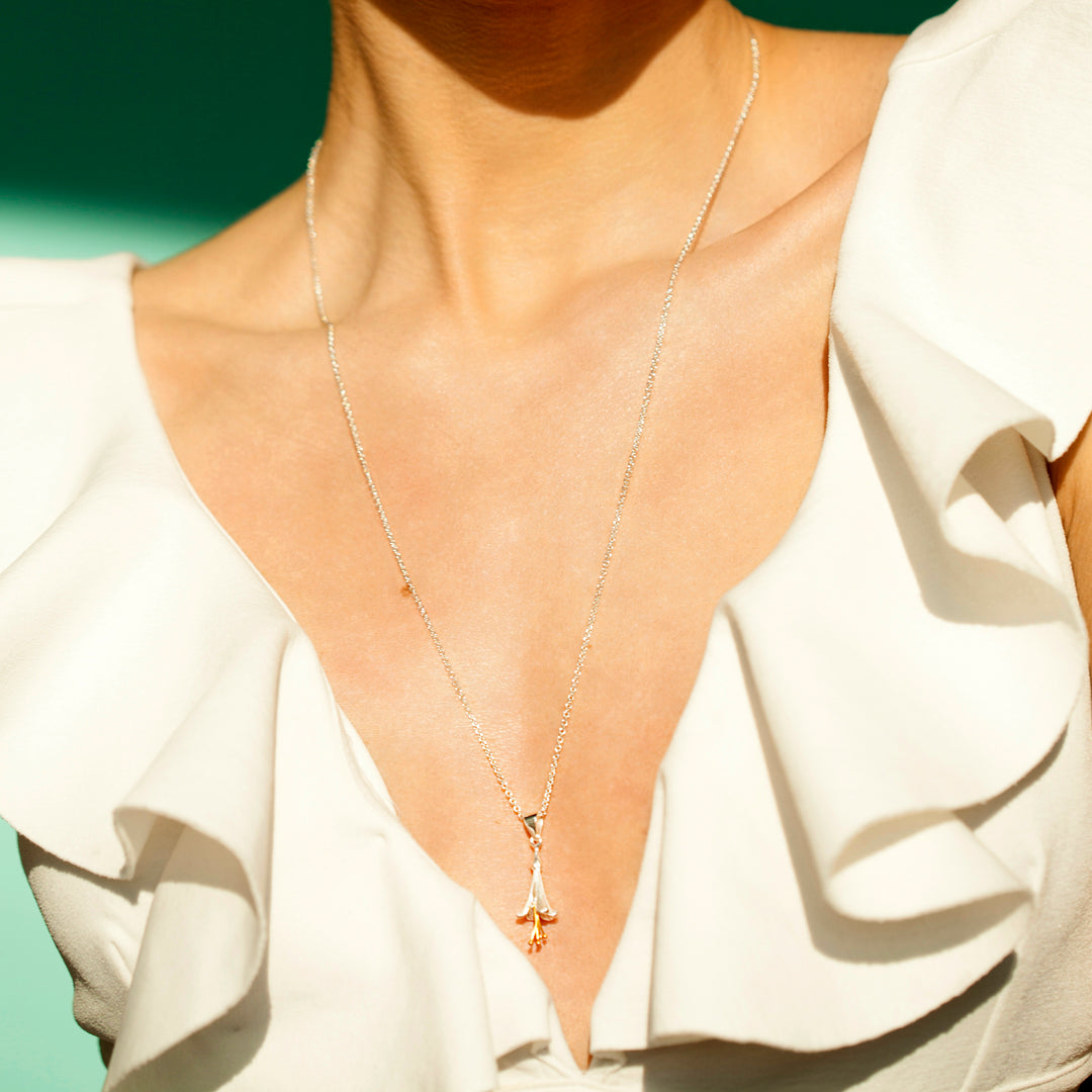 Close up of model wearing silver fuchsia necklace with a white dress