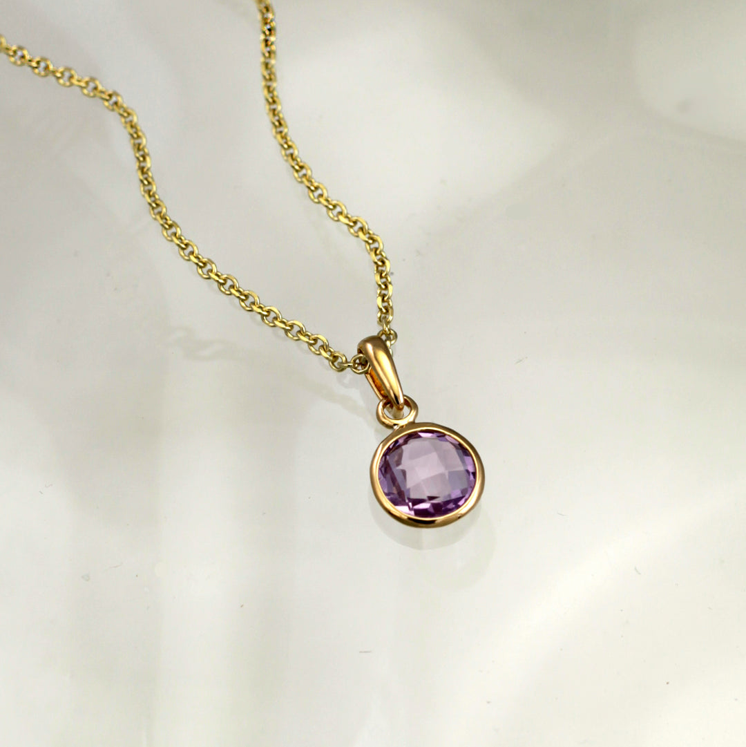 amethyst and gold plated silver pendant and chain on gray background