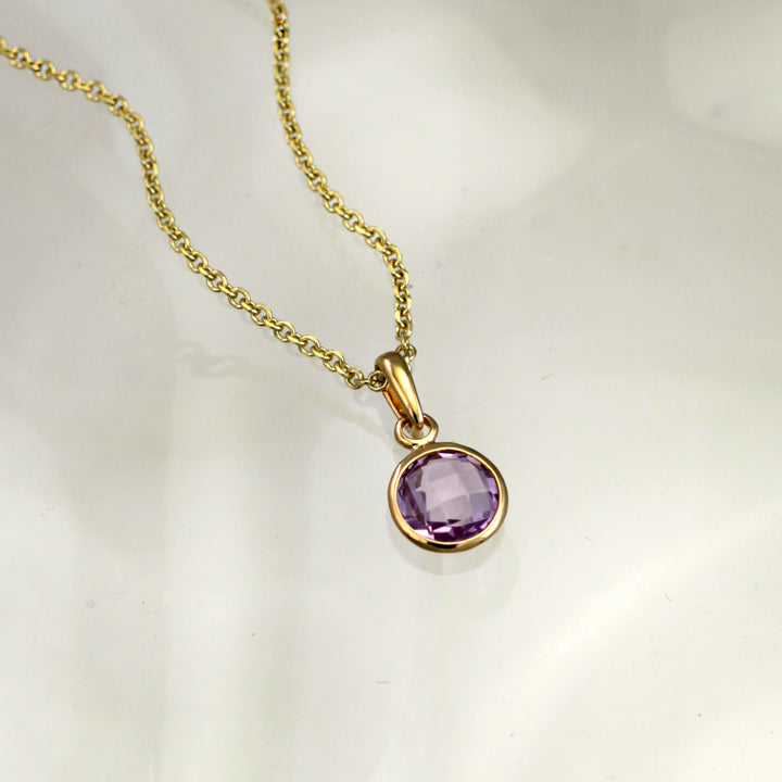 amethyst and gold plated silver pendant and chain on gray background