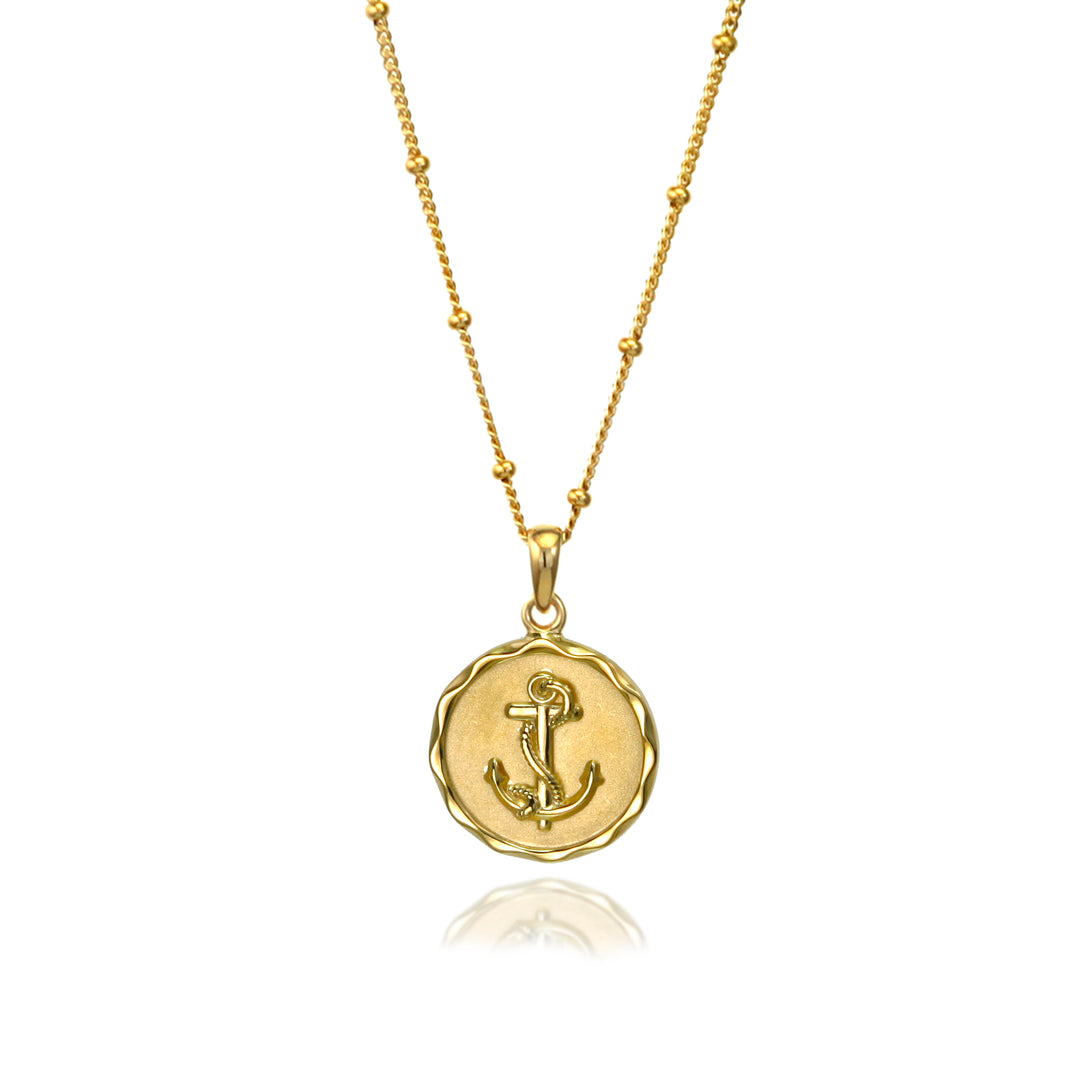 Gold anchor necklace with a beaded chain on a white background