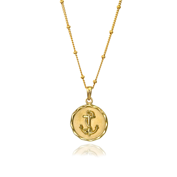 Gold anchor necklace with a beaded chain on a white background