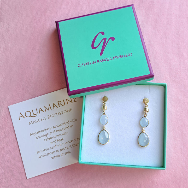Natural aquamarine and gold earrings in Christin Ranger Jewellery gift box and card on a pink background.