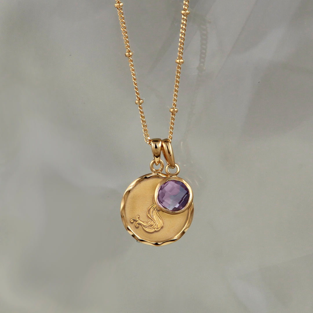 Gold Aquarius necklace with an amethyst February birthstone on gray background