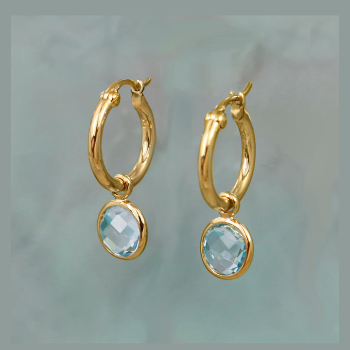 Gold snap-post hoop  earrings with blue topaz gemstones on an aqua background