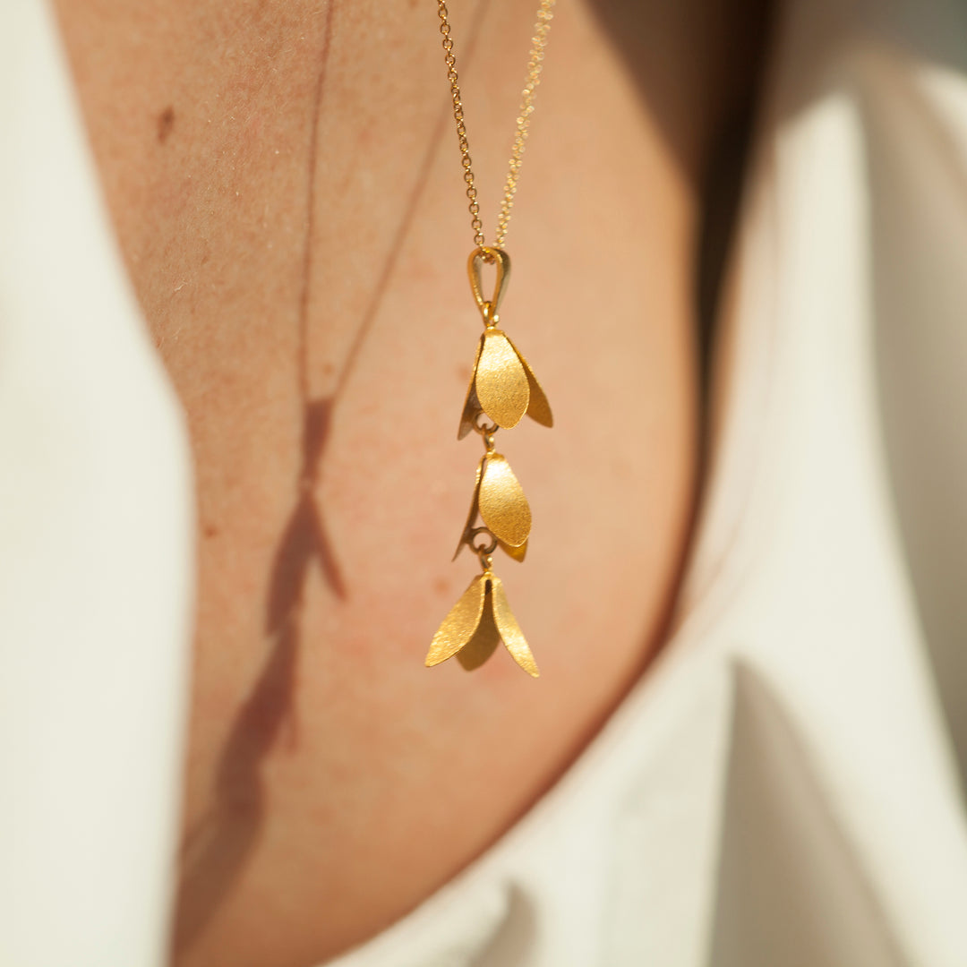 Close-up of a woman wearing a gold catkin dangle necklace