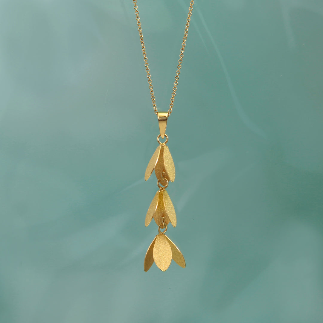 Gold catkin flower necklace on a green background