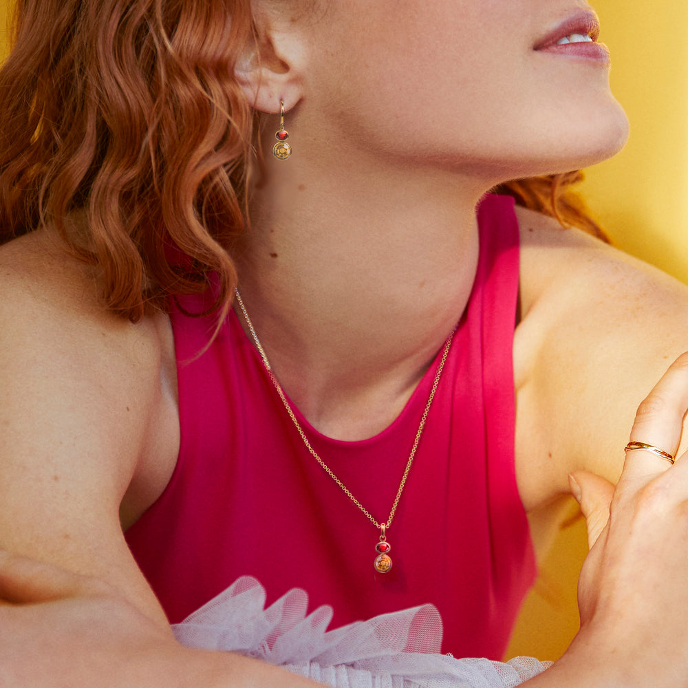 Woman wearing a pink top with gold jewelry against a yellow background