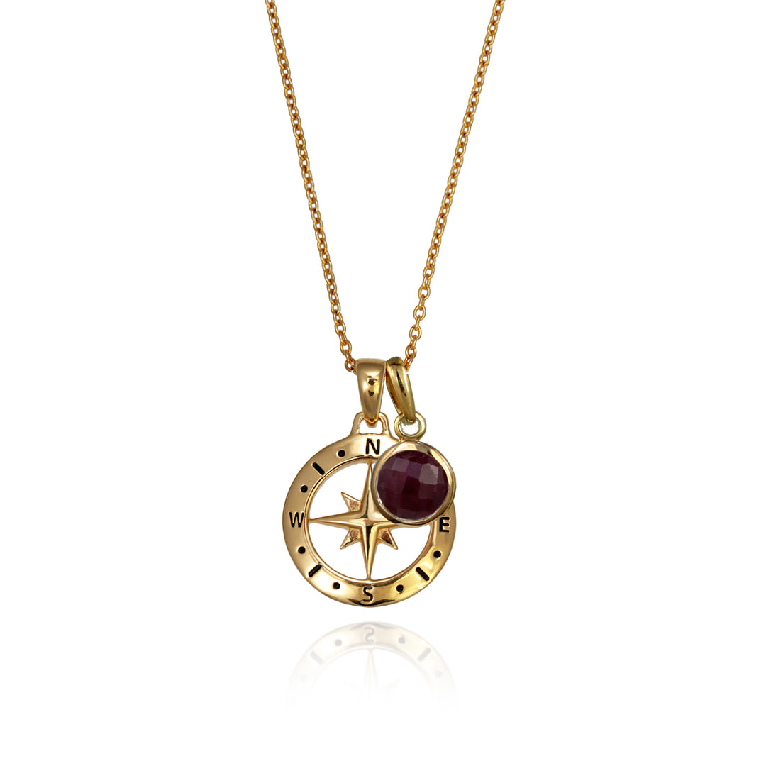 A gold versible compass necklace with a genuine ruby july birthstone charm and chain against a white background