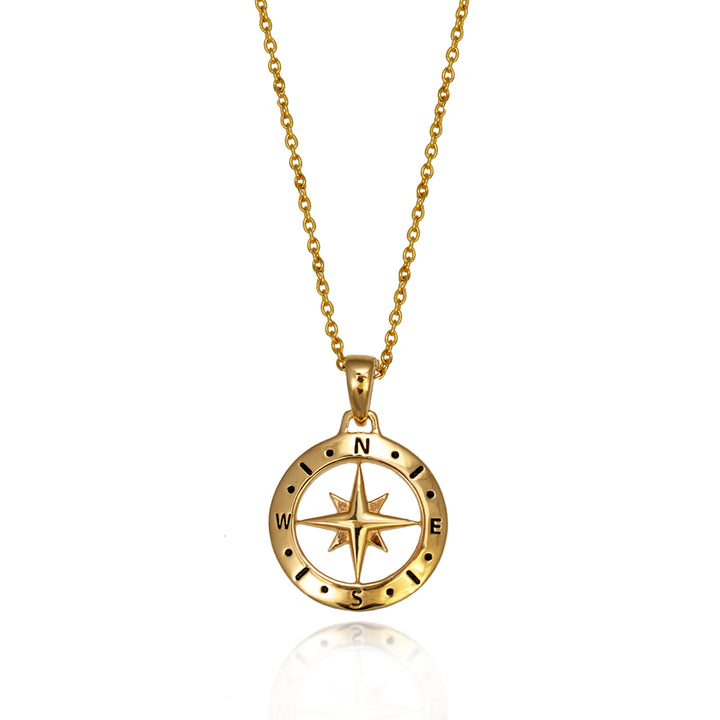 Gold compass necklace and chain against a white background