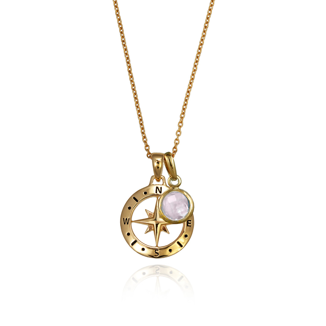 A gold versible compass necklace with a pale rose quartz october  birthstone charm and chain against a white background