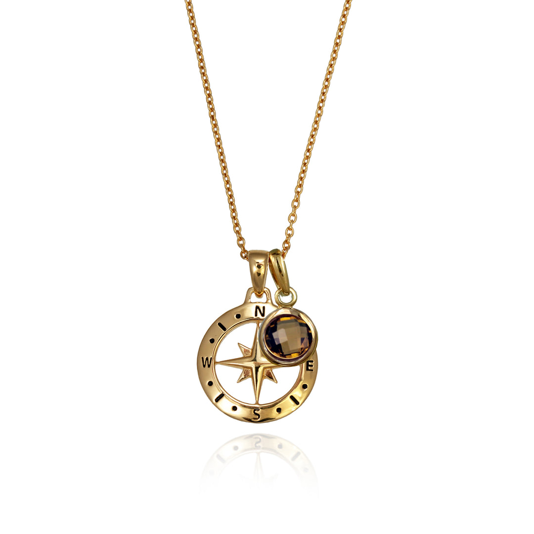 A gold versible compass necklace with a brown quartz november  birthstone charm and chain against a white background